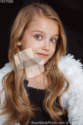 Image of Little smiling girl posing in white outfit on black studio background
