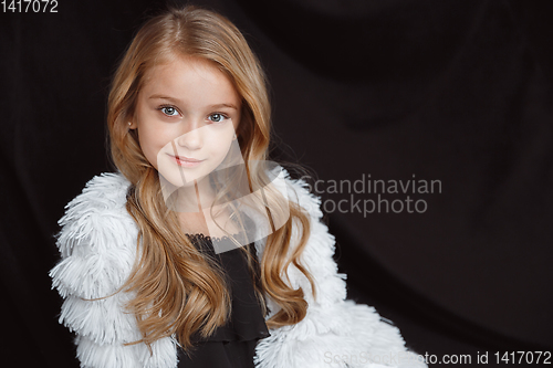 Image of Little smiling girl posing in white outfit on black studio background
