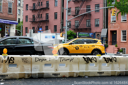 Image of Graffiti slogan - Deport Trump! - on a traffic barrier on 7th Av