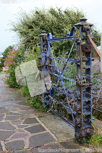 Image of Weathered, locked blue gate covered with peeling blue paint