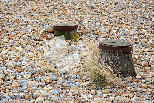 Image of Tops of two groyne sea defences visible on a shingle beach