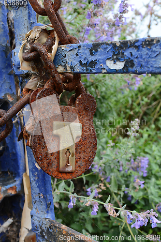 Image of Rusted, broken padlock fastened to a metal chain on a gate with 