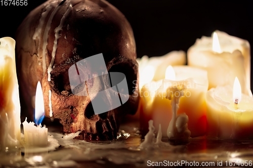 Image of Human skull against dark background in candle light closeup