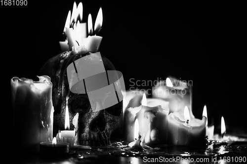 Image of Candles and human skull in darkness closeup in black and whiter