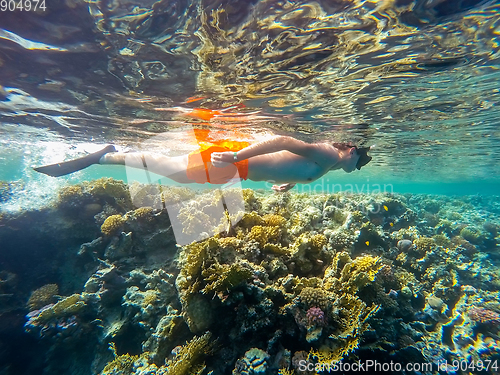 Image of Young boy Snorkel swim in shallow water with coral fish