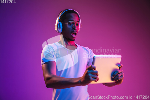 Image of Young african-american man\'s listening to music in neon light