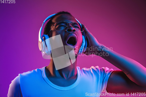 Image of Young african-american man\'s listening to music in neon light
