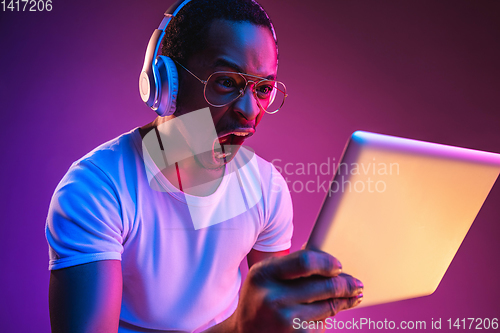 Image of Young african-american man\'s listening to music in neon light