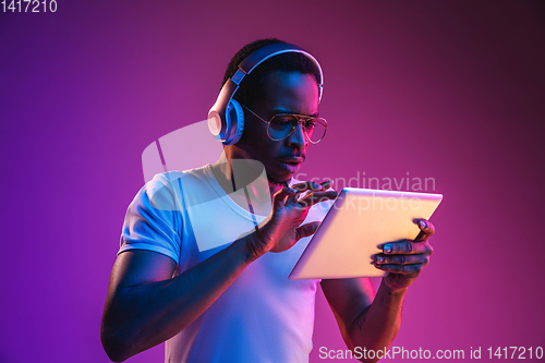 Image of Young african-american man\'s listening to music in neon light