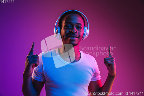 Image of Young african-american man\'s listening to music in neon light