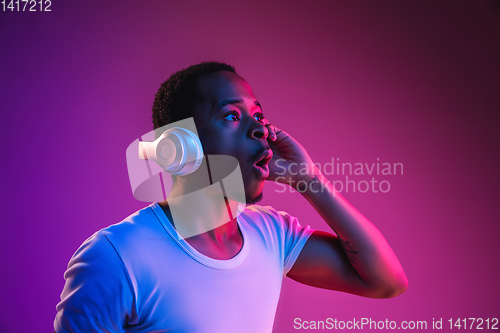 Image of Young african-american man\'s listening to music in neon light