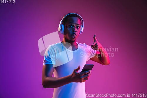 Image of Young african-american man\'s listening to music in neon light
