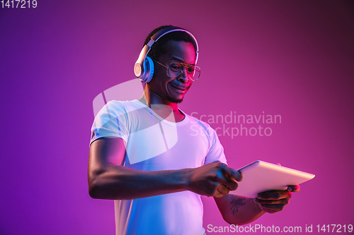 Image of Young african-american man\'s listening to music in neon light
