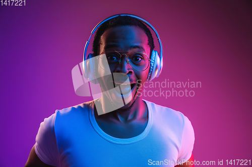 Image of Young african-american man\'s listening to music in neon light