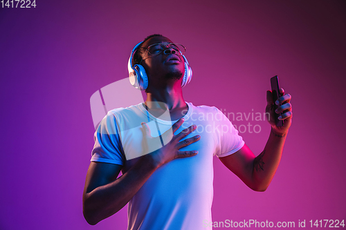 Image of Young african-american man\'s listening to music in neon light
