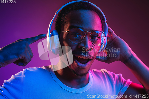 Image of Young african-american man\'s listening to music in neon light