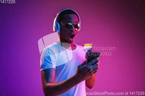 Image of Young african-american man\'s listening to music in neon light