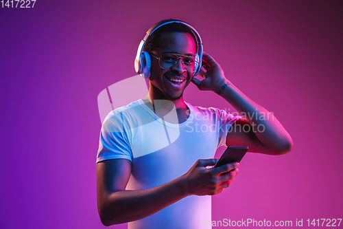 Image of Young african-american man\'s listening to music in neon light