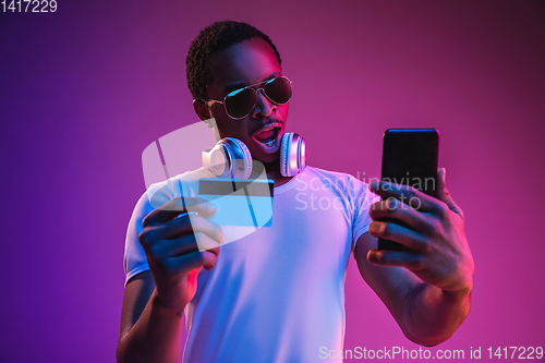 Image of Young african-american man\'s listening to music in neon light