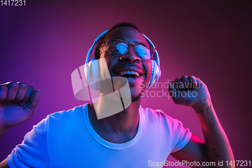 Image of Young african-american man\'s listening to music in neon light