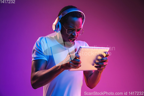 Image of Young african-american man\'s listening to music in neon light