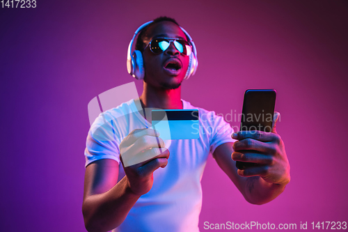 Image of Young african-american man\'s listening to music in neon light