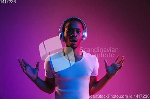 Image of Young african-american man\'s listening to music in neon light