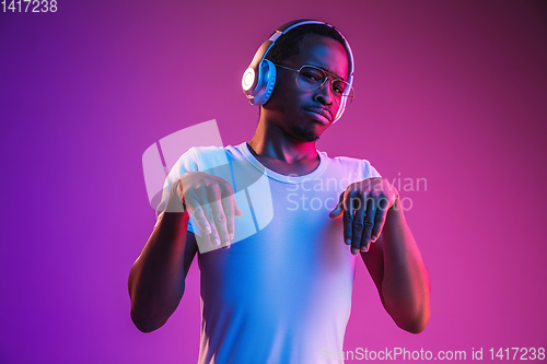 Image of Young african-american man\'s listening to music in neon light