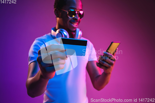 Image of Young african-american man\'s listening to music in neon light