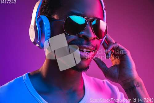 Image of Young african-american man\'s listening to music in neon light