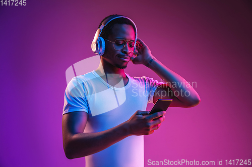 Image of Young african-american man\'s listening to music in neon light