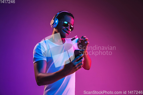 Image of Young african-american man\'s listening to music in neon light