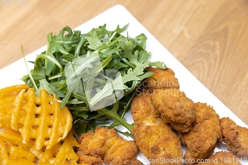 Image of Chicken nuggets with salad on table