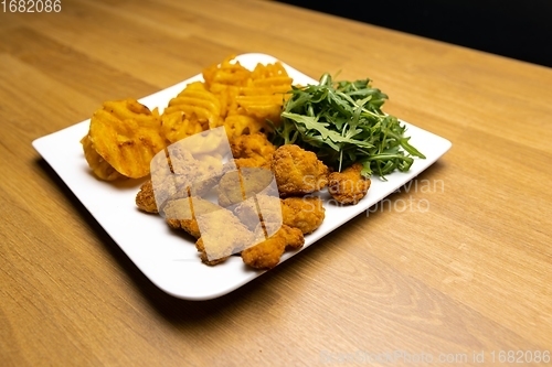 Image of Chicken nuggets with salad on table closeup