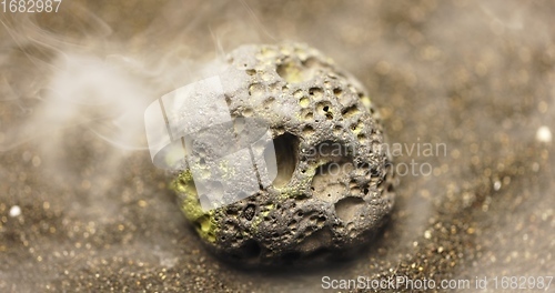 Image of Smoke whirling around small meteorite stone