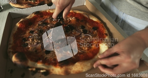 Image of Delicious pizza being sliced up on the table