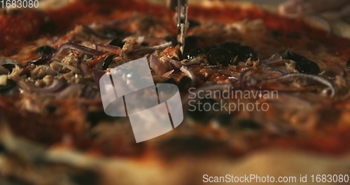 Image of Delicious pizza being sliced up on the table