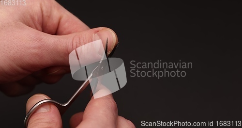 Image of Man cuts fingernail for himself