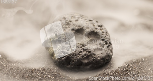 Image of Smoke whirling around small meteorite stone