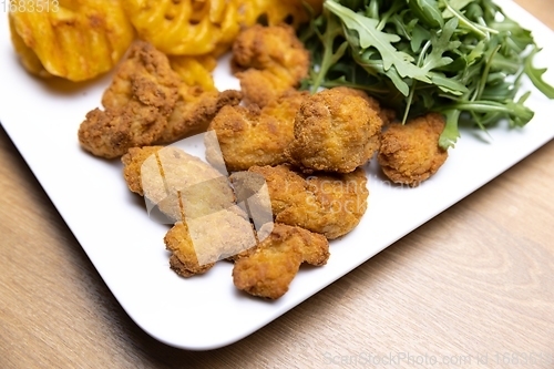 Image of Chicken nuggets with salad on table closeup