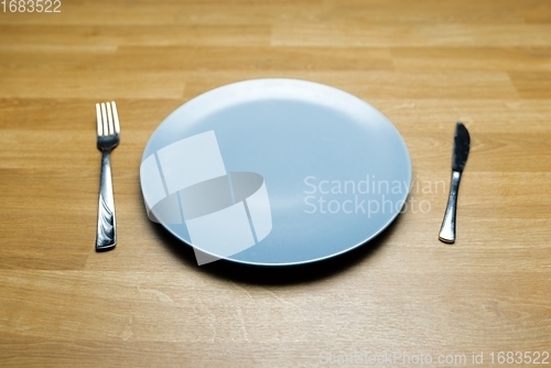 Image of Empty dish on table with fork and knife