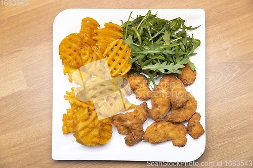 Image of Chicken nuggets with salad on table closeup