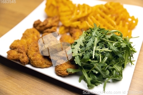 Image of Chicken nuggets with salad on table closeup