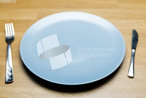 Image of Empty dish on table with fork and knife