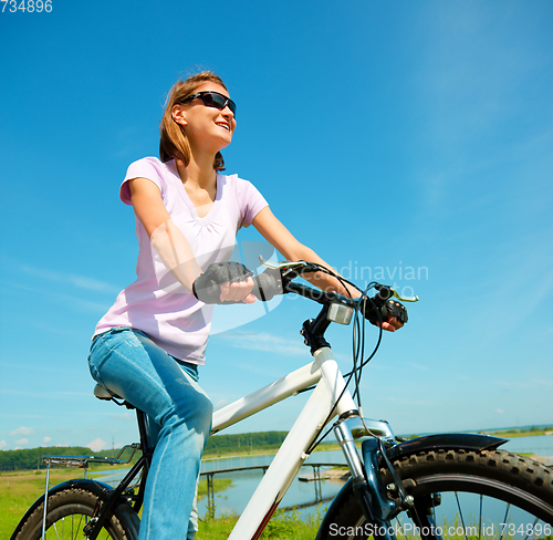 Image of Young woman is sitting on her bicycle