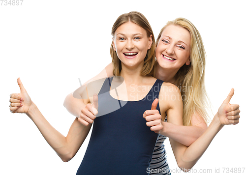Image of Two young happy women showing thumb up sign