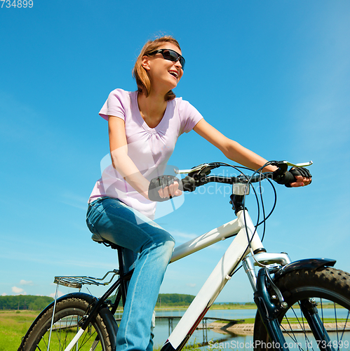 Image of Young woman is sitting on her bicycle