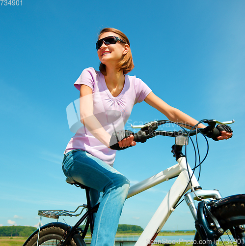 Image of Young woman is sitting on her bicycle