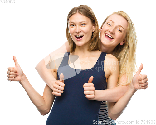 Image of Two young happy women showing thumb up sign