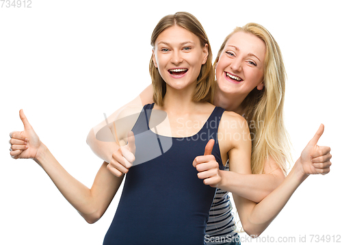 Image of Two young happy women showing thumb up sign